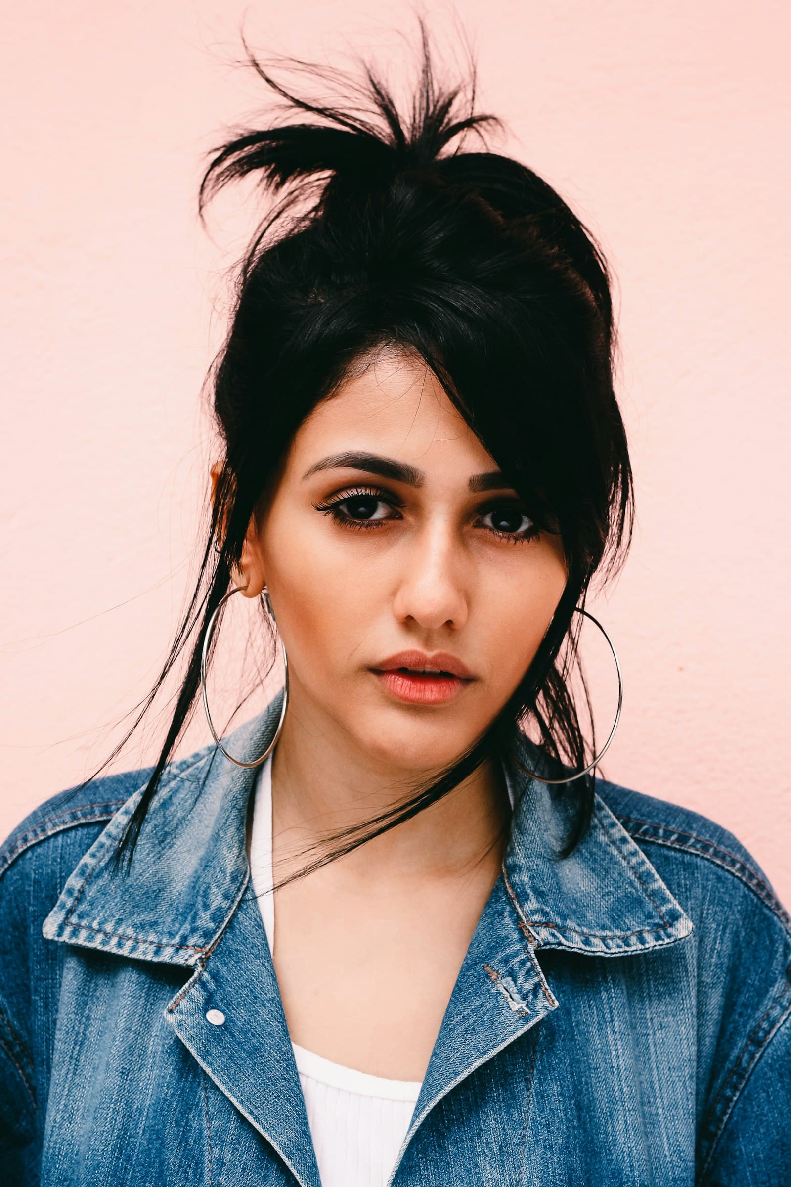 Portrait in a denim jacket against a pink wall