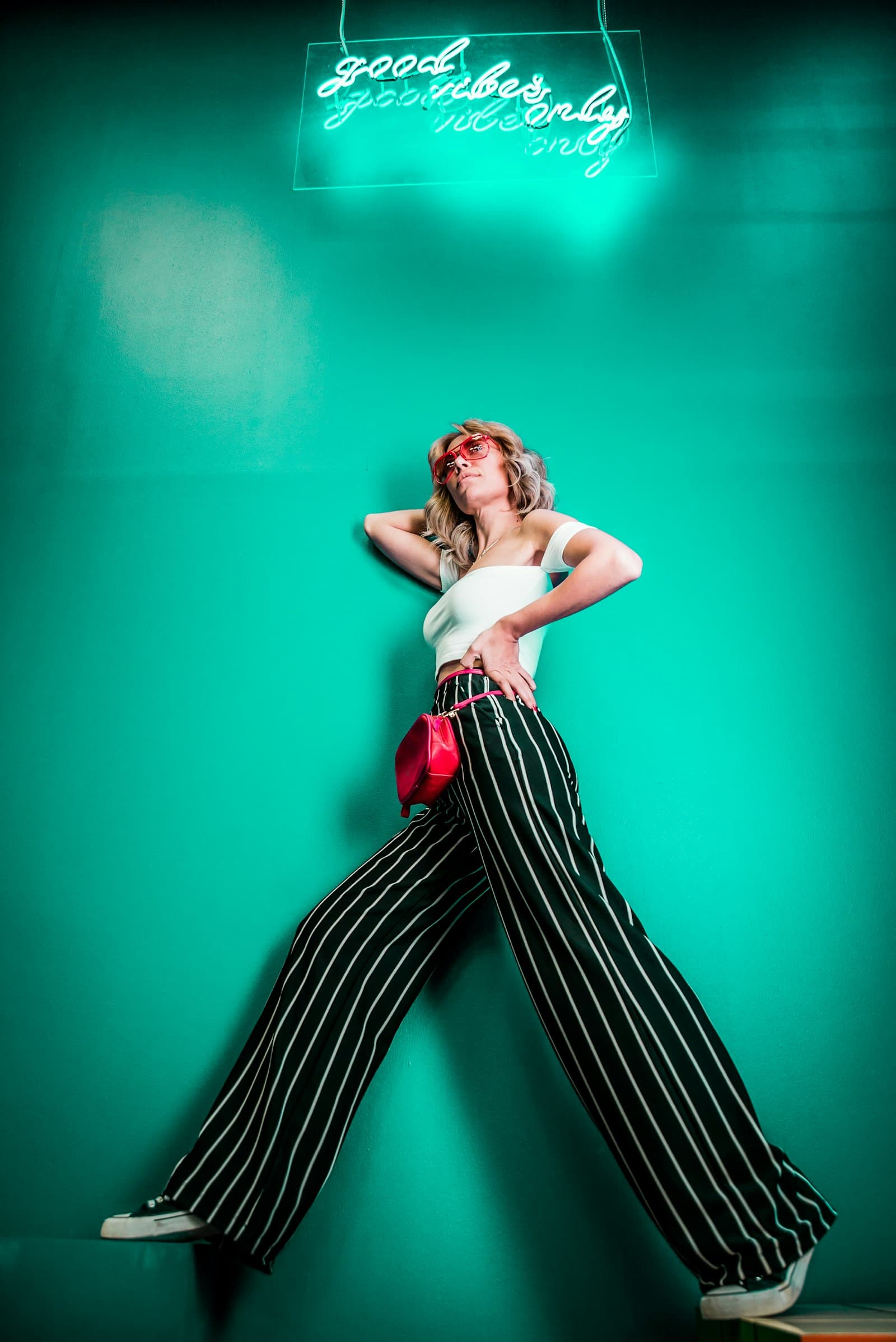 Striped wide-leg trousers against a green wall